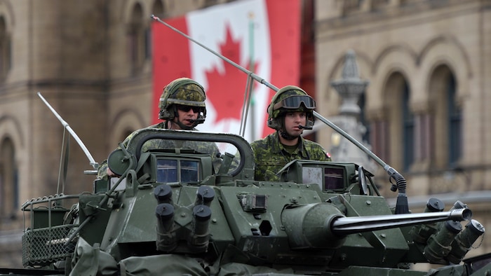 Des soldats canadiens à bord d'un véhicule blindé léger lors d'un défilé.