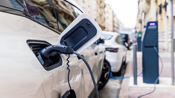 Recharge d'une voiture électrique à la borne électrique dans la rue.