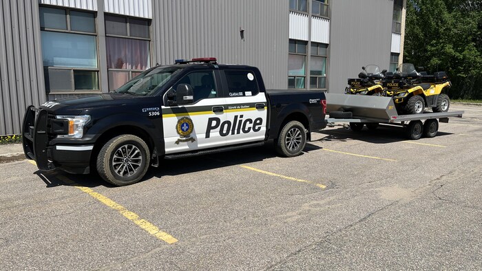 Une camionnette de la Sûreté du Québec et des véhicules tout-terrain sur une remorque.