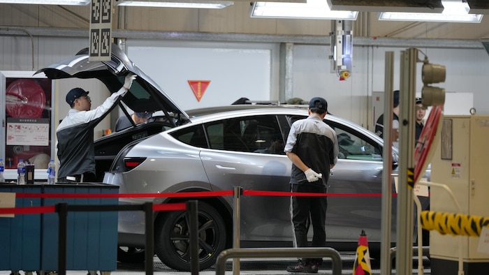 Des ouvriers inspectent la Tesla Model Y dans une usine d'assemblage Gigafactory de Tesla, à Shanghai, en Chine, le mardi 14 avril 2026.