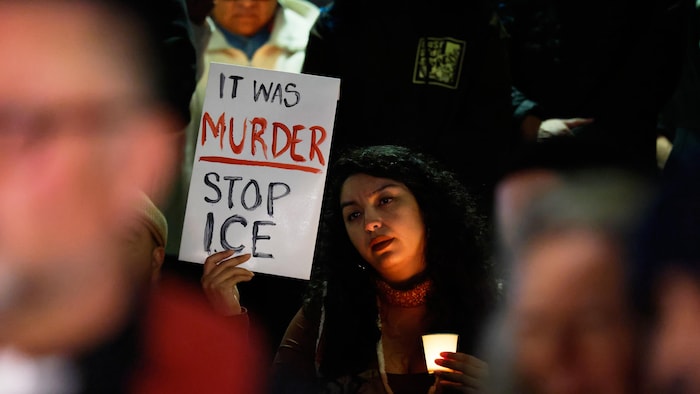 Une manifestante tient une pancarte indiquant : « C'était un meurtre Arrêtez l'ICE ».