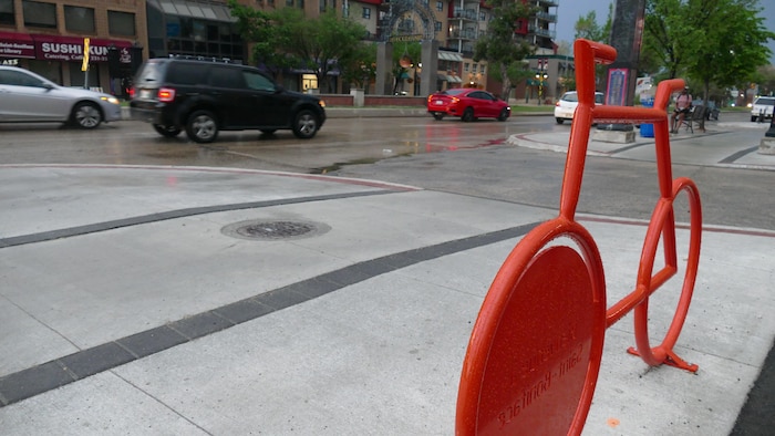 Un vélo rouge en métal avec un boulevard en arrière-plan.