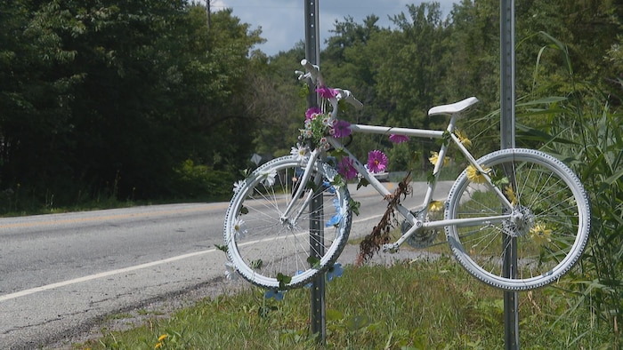 Un vélo blanc est installé aux abords de la rue College.