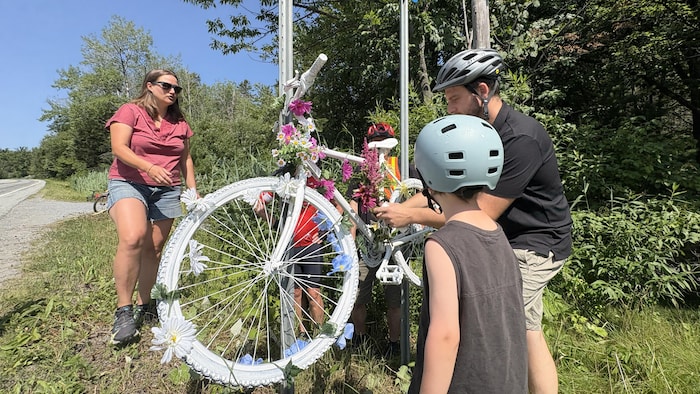 Un vélo blanc installé sur le bord d'une rue. 