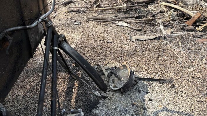 Un vélo carbonisé repose au milieu des ruines à East Trout Lake.
