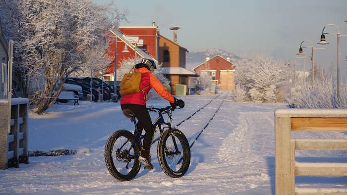 Une femme de dos sur un vélo en hiver, à Whitehorse, au Yukon