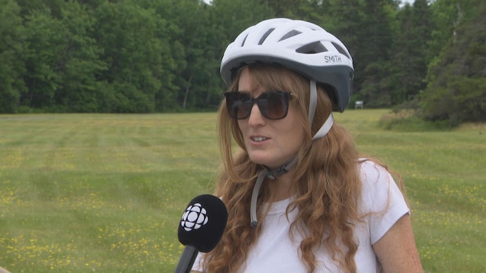 Une femme portant un casque de vélo, en entrevue.