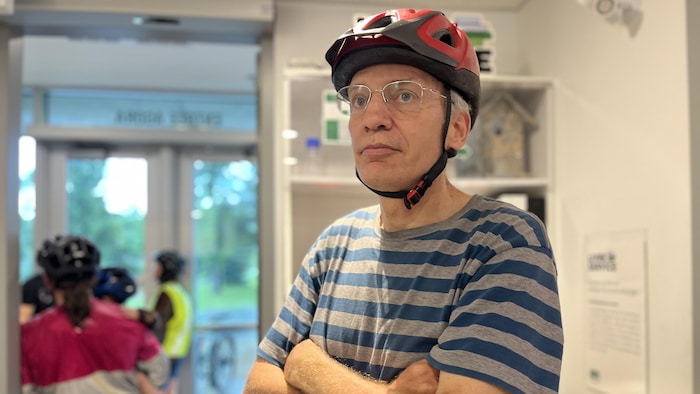 Fabien Burnotte porte son casque de vélo. Il se tient debout les bras croisés, à l'intérieur de l'Université de Sherbrooke.