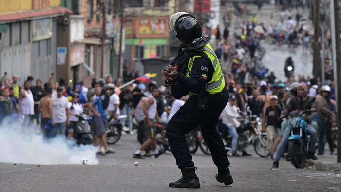 Un policier lance des gaz lacrymogènes sur la foule.