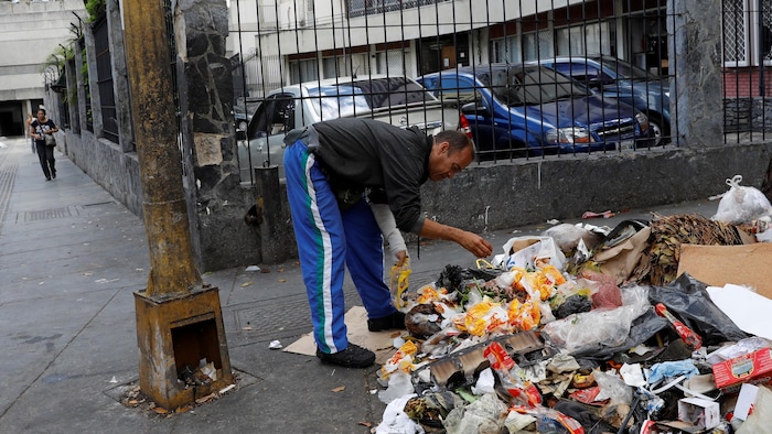 Un homme est penché sur un tas de déchets.