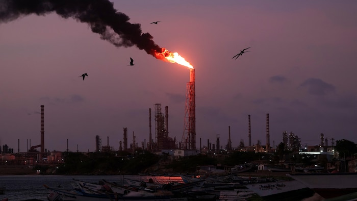 Une torche de gaz brûle dans une raffinerie.