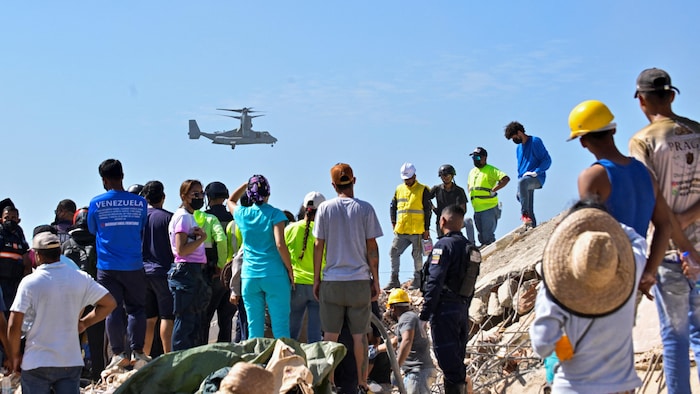 Des personnes observent un hélicoptère de sauvetage dans le ciel.