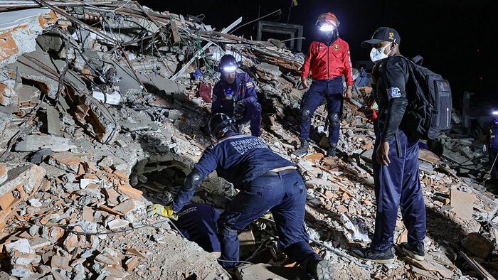 Des pompiers recherchent des victimes parmi les décombres d'un bâtiment effondré.
