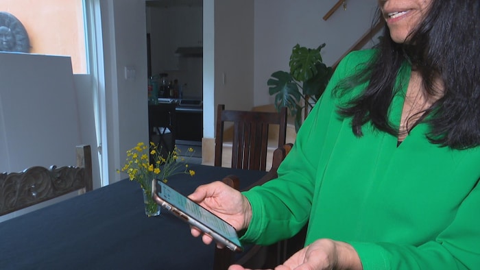 Une femme tient un téléphone cellulaire dans sa main droite.