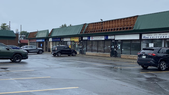 De grands morceaux de la toiture en tôle d'un centre commercial sont manquants.