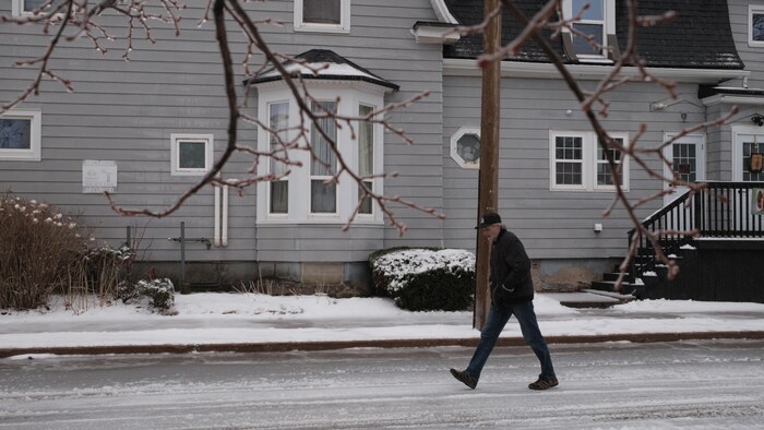 Un homme qui marche sur une rue glacée.