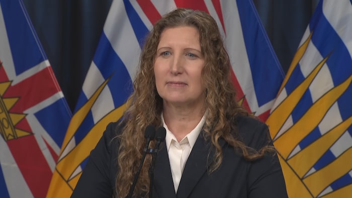 Bridget Parrish est devant des drapeaux de la Colombie-Britannique, et derrière un podium