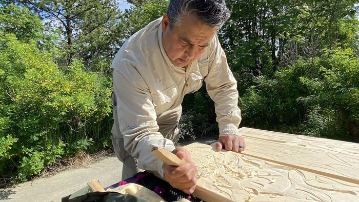 Vernon Asp tient un outil pour tailler le bois.