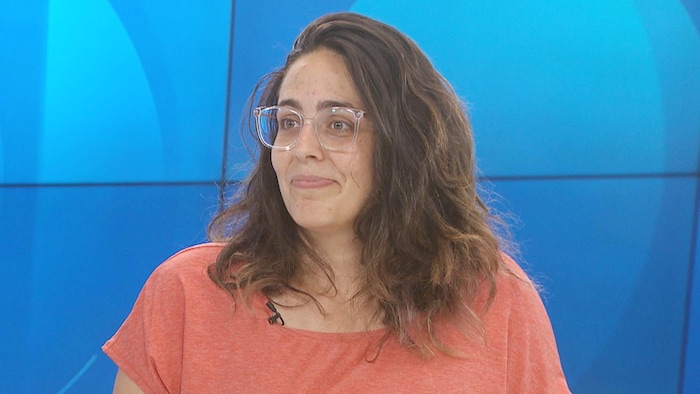 Véronique Chadillon-Farinacci sur un plateau de télévision, debout devant un fond bleu.