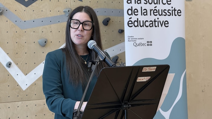 Une femme parle dans un micro à son auditoire.  
