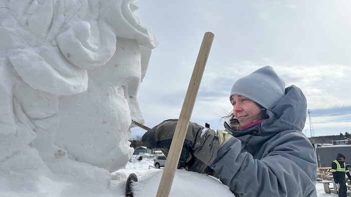 Véronique Gagné travaille sur le visage d'un ange en neige en souriant.