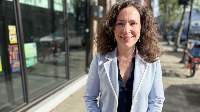 Véronique Proulx pose avec un large sourire sur le trottoir devant les studios de Radio-Canada à Rouyn-Noranda.