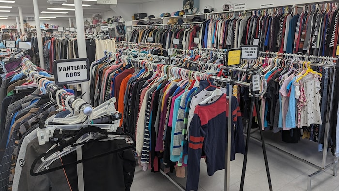 Des vêtements sont suspendus sur des présentoirs.