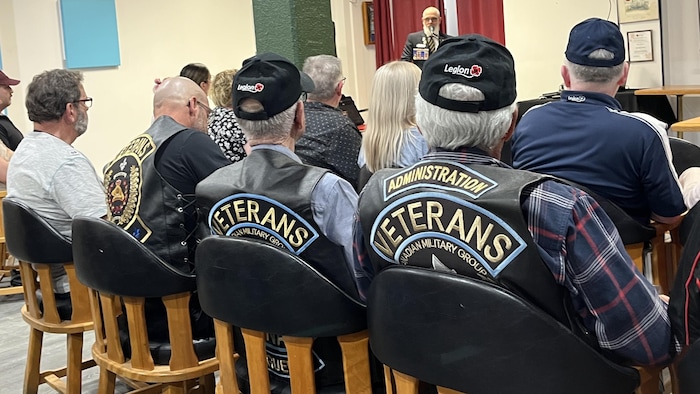 Des vétérans avec leur veste sont assis dans une salle.