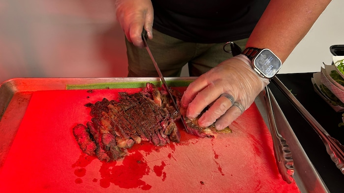 Une personne coupe du boeuf.