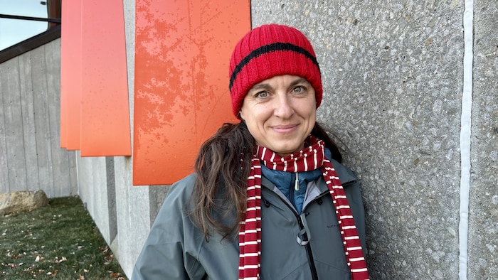 Une femme debout près d'un bâtiment en pierre.