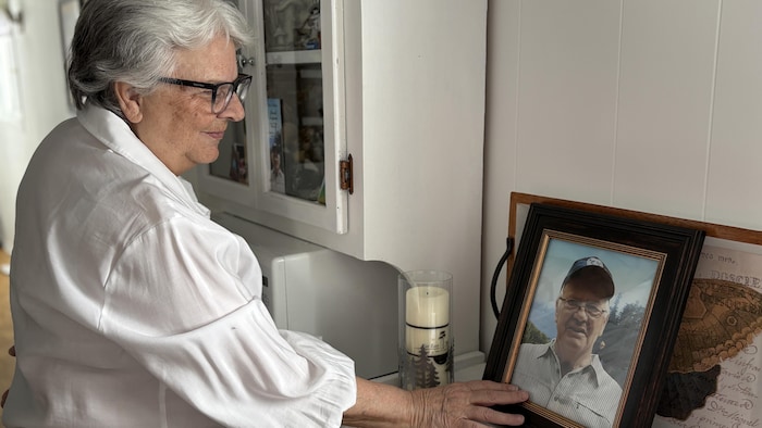 Victoire Allen pose la main sur la photo de son défunt mari.