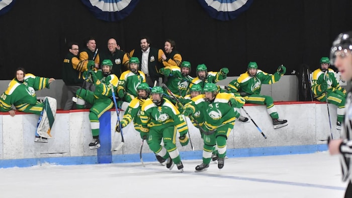 Une dizaine de joueurs des Conquérants sautent sur la glace pour célébrer leur victoire.