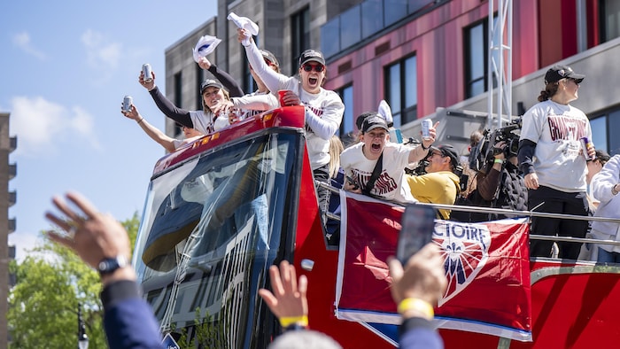 Des supporters applaudissent la Victoire de Montréal, à bord d'un autobus.