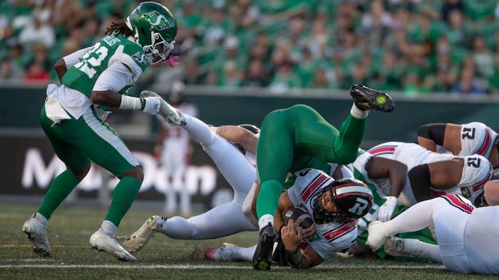 Le quart-arrière des Rouge et Noir d’Ottawa, Bryson Barnes (au bas de l’image), inscrit un touché contre les Roughriders de la Saskatchewan pendant la première demie d’un match de la LCF, vendredi, à Regina.