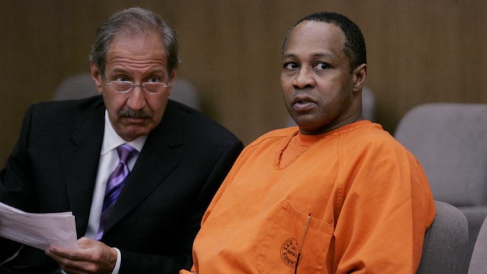 Victor Willis, revêtant un habit orange de détenu, est assis dans une salle de palais de justice.
