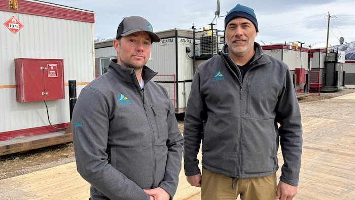 Deux hommes devant des maisons mobiles.