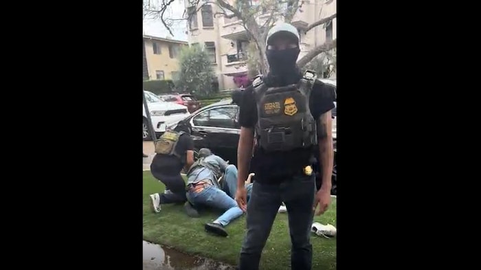 Image prise d'une vidéo montrant l'arrestation d'un couple de demandeurs d'asile iraniens à Los Angeles, le 23 juin 2025. Ici, on voit des hommes masqués détenant une femme au sol.