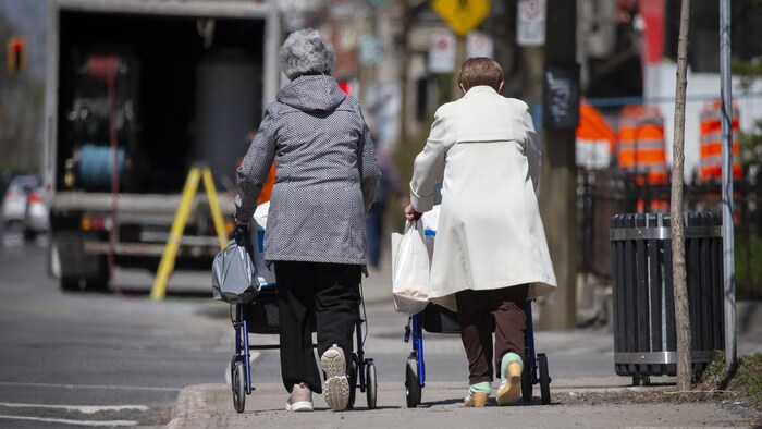 Deux personnes âgées marchent dans le centre-ville de Montréal.
