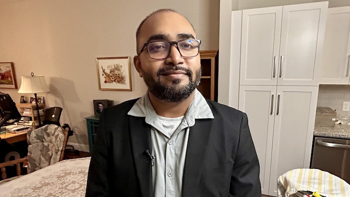 Vimal Parmar est debout dans un domicile et sourit.