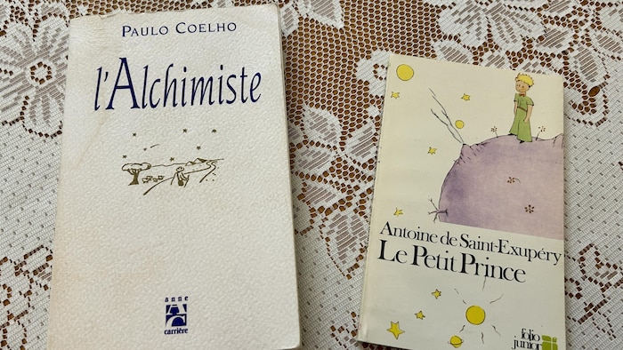 Les livres L'Alchimiste de Paulo Coelho et Le Petit Prince d'Antoine de Saint-Exupéry sont sur une table.