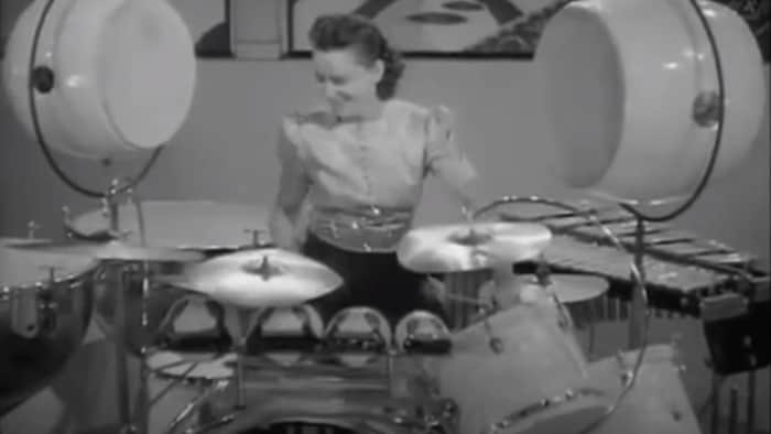 Une femme distinguée joue de la batterie.