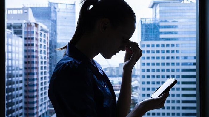 Une femme s'incline par déception devant son cellulaire.