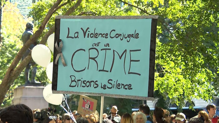Une pancarte affiche "la violence conjugale est un crime, brisons le silence".