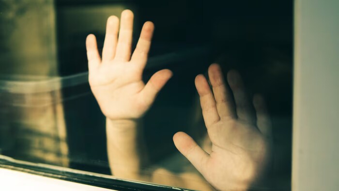 Des mains appuyées dans une fenêtre.