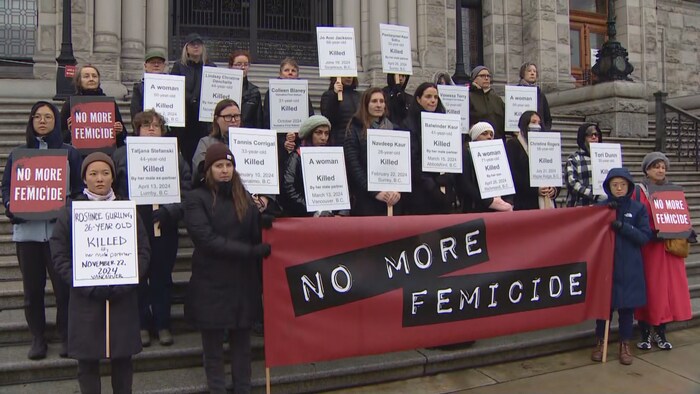 Des femmes tiennent des pancartes devant le palais législatif à Victoria, le 25 novembre 2024. 
