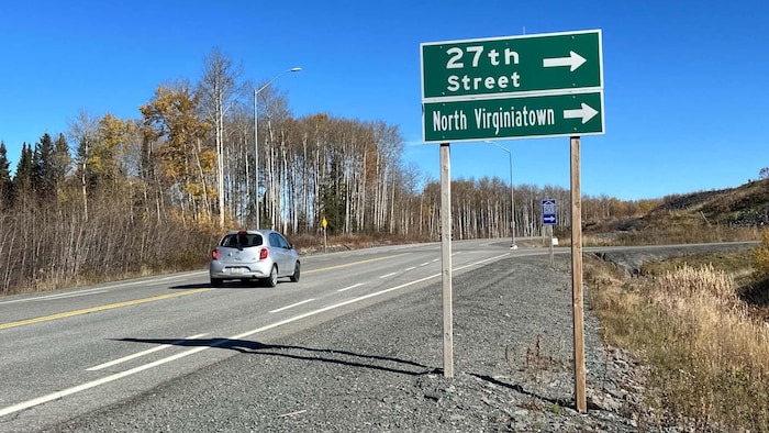 Une voiture roulant sur une route et une affiche indiquant «27th Street et North Virginiatown», avec des flèches qui pointent vers la droite.