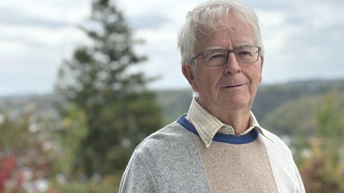 Un homme pose devant des arbres.