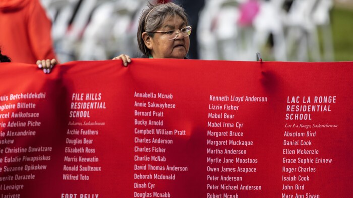 Una persona sostiene una pancarta con los nombres de los niños indígenas.