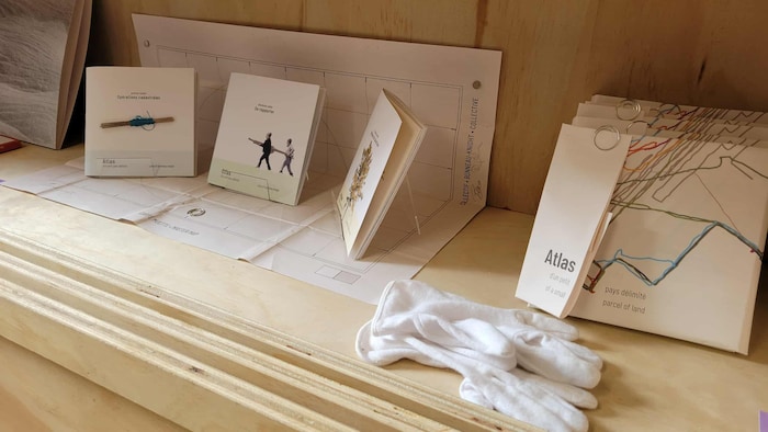 Petits livres d'artiste empil&eacute;s dans une &eacute;tag&egrave;re de bois.