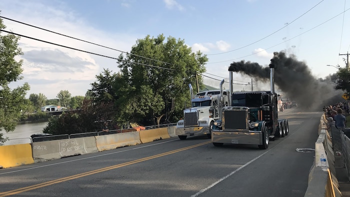 Deux tracteurs de camion en pleine course d'accélération dans la rue d'un village.